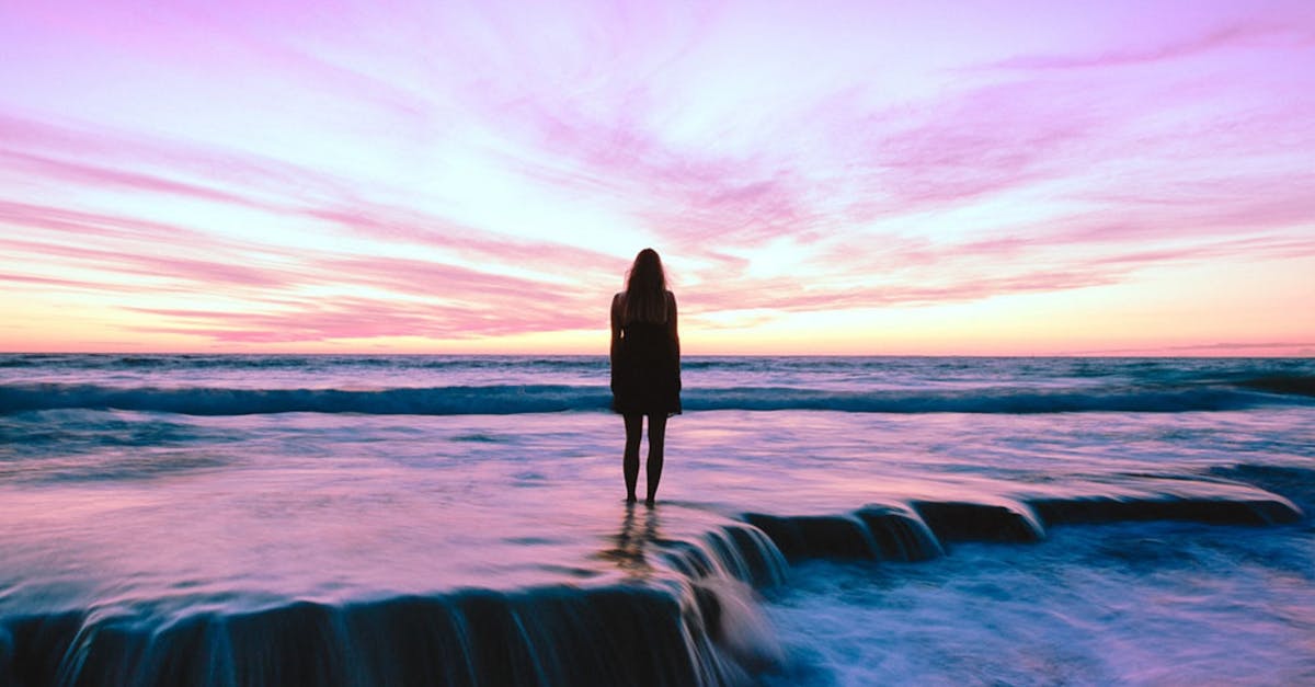 元カノに連絡するか迷いながら夕陽を見つめている男性の後ろ姿