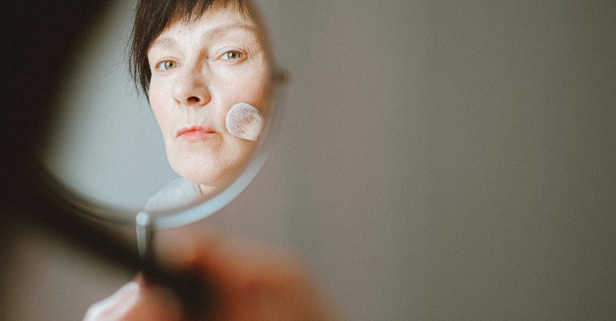 50代の女性がメイクを仕上げる様子。肌がしっとりしてファンデーションがなじむリアルなシーン。