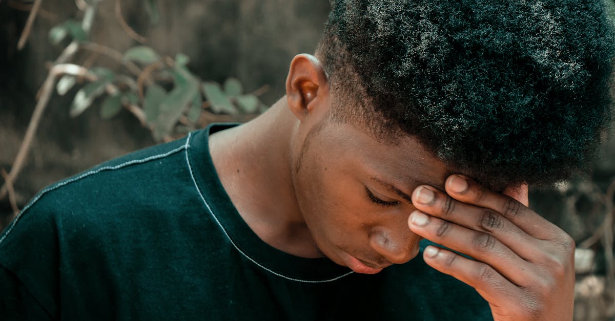 寝ても疲れが取れずに悩んでいる男性が頭を抱えている様子