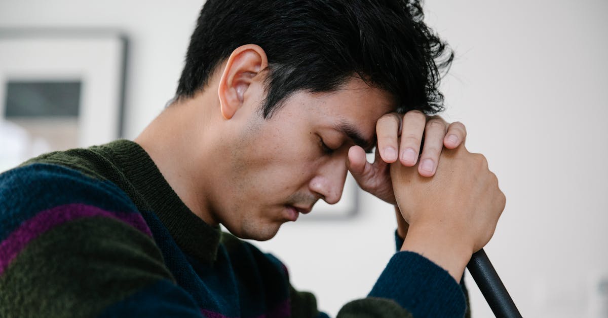 寝ても疲れが取れずに悩んでいる男性が頭を抱えている様子